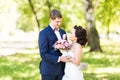 Wedding couple hugging, the bride holding a bouquet of flowers, groom embracing her Royalty Free Stock Photo