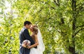 Wedding couple hugging, the bride holding a bouquet of flowers, groom embracing her Royalty Free Stock Photo