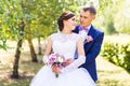 Wedding couple hugging, the bride holding a bouquet of flowers, groom embracing her outdoors Royalty Free Stock Photo