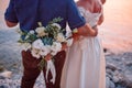 Wedding couple hugging, the bride holding a bouquet of flowers in her hand, the groom embracing her Royalty Free Stock Photo