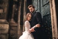 Wedding couple hugs near the vintage green door. Stone walls in ancient town background. bride with long hair in lace dress and Royalty Free Stock Photo