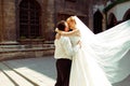 A wedding couple kiss in the lights of morning sun standing behind an old cathedral Royalty Free Stock Photo