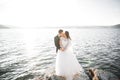 Wedding couple kissing and hugging on rocks near blue sea Royalty Free Stock Photo