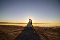 Wedding couple kissing on the sea beach watching sunset. Sunny summer photo. Bride with hair down in off shoulder dress with train Royalty Free Stock Photo