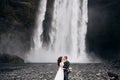 Wedding couple near Skogafoss waterfall. Destination Iceland wedding. The groom kisses the bride. Royalty Free Stock Photo