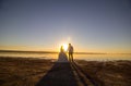 Wedding couple on the sea beach watching sunset. Sunny summer photo. Bride with hair down in off shoulder dress with train. Ocean Royalty Free Stock Photo