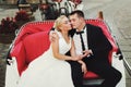 A wedding couple sit in the red open carriage