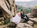 Wedding couple sitting at rocky mountains against the sky. Cute romantic moment. Royalty Free Stock Photo