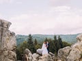 Wedding couple standing at rocky mountains against the sky. Cute romantic moment. Royalty Free Stock Photo