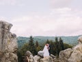 Wedding couple standing at rocky mountains against the sky and kissing. Cute romantic moment. Royalty Free Stock Photo