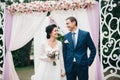 Wedding couple standing under an arch of fresh flowers Royalty Free Stock Photo