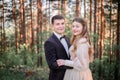 Wedding couple stands between the high mountain trees