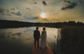 Wedding couple stands and looks at each other in the sunset. Twilight over the lake. White dress and bridal veil with lace. Hands Royalty Free Stock Photo