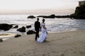 Wedding couple walking along beach holding hands. Royalty Free Stock Photo