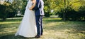 Wedding couple walking in the green park. Curvy bride in white lace dress and groom are holding hands. Overweight happy people. Royalty Free Stock Photo