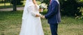 Wedding couple walking in the green park. Curvy bride in white lace dress and groom are holding hands. Overweight happy people. Royalty Free Stock Photo