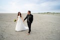 Wedding couple walking on sandy beach. Bride and groom looking to each other and smiling. Barefoot husband. Wedding day Royalty Free Stock Photo