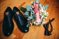 Wedding day accessories. Groom`s shoes with bouquet on the wooden background. Golden rings and bow tie are nearby. Stylish things Royalty Free Stock Photo