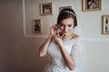 Wedding day. Beautiful bride trying on earrings