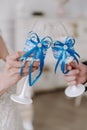 Wedding day. Hands of the bride and groom are holding wedding glasses with champagne, decorated in blue. Blue bow on glasses. Royalty Free Stock Photo