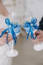 Wedding day. Hands of the bride and groom are holding wedding glasses with champagne, decorated in blue. Blue bow on glasses. Royalty Free Stock Photo