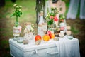 Wedding decor with bottles, glasses, roses, vases and peaches on