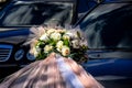 Wedding decor: bouquet of artificial flowers roses, decorated with pink and white tulle, is attached to the hood of black car Royalty Free Stock Photo