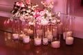 Wedding decor, burning candles in glass flasks with flowers composition on the floor. Coziness and style. Modern event design. Royalty Free Stock Photo