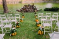 Wedding decoration with autumn pumpkins and flowers. Ceremony outdoor in the park. White chairs for guests Royalty Free Stock Photo