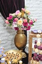 Wedding decoration with multicolored roses in vase, pastel colored cupcakes, meringues, muffins and macarons