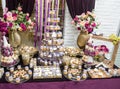 Wedding decoration with multicolored roses in vase, pastel colored cupcakes, meringues, muffins and macarons