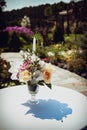 Wedding decorations. A bouquet of flowers in a vase with a candle on the festive table. Royalty Free Stock Photo