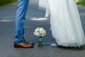 Wedding details: classic brown and blue shoes of bride and groom. Bouquet of roses standing on the ground between them. Newlyweds Royalty Free Stock Photo