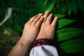 Wedding details - closeup of hands of newly-married with gold rings on green background