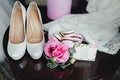 Wedding details, decoration. Bouquet of pink roses, bridal accessories and macaroons stand on a wooden table. Soft focus