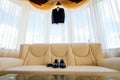 Wedding details. Groom accessories. Shoes and belt on leather sofa under a suit hanging on window