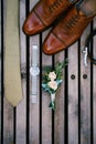 Wedding details of the groom - boutonniere, shoes, tie and watch on a wooden background, top view.