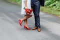 Wedding details: stylish red and brown shoes of bride and groom. Newlyweds standing in front of each other. Bridal bouquet of rose Royalty Free Stock Photo