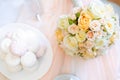 Wedding details. Top view of bride`s bouquet of light roses flowers on the table with perfumes and arshmallow sweets. Flat lay. S Royalty Free Stock Photo
