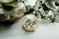 Wedding details. two classic gold wedding rings in a glass box and a bouquet of white flowers and greenery Royalty Free Stock Photo