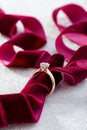 Wedding diamond ring on white glossy background with burgundy ribbon Royalty Free Stock Photo