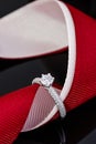 Wedding diamonds ring on black background with red ribbon