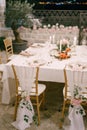 Wedding dinner table reception. Draping brown chairs Chiavari Tiffany with white cloth to floor, decoration with rose