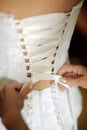 Wedding dress corset close up. Preparation of the bride. Bridesmaid tying bow on wedding dress. Bride in the white dress.