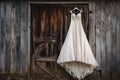 wedding dress on hanger against a rustic barn wall