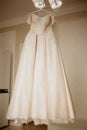 Wedding dress on hanger in the bride room. On her wedding day