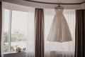 Wedding dress on hanger near window in the bride room. On her wedding day