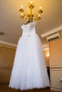 Wedding dress hanging on the chandelier. bride accessories. charges of the bride. bride`s morning