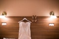 Wedding dress hanging on the wall in the room and bridal beige shoes. Image of the bodice of a beige wedding dress on a wooden whi Royalty Free Stock Photo