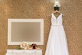 Wedding dress hanging on wall with texture and bouque, perfume and jewelry